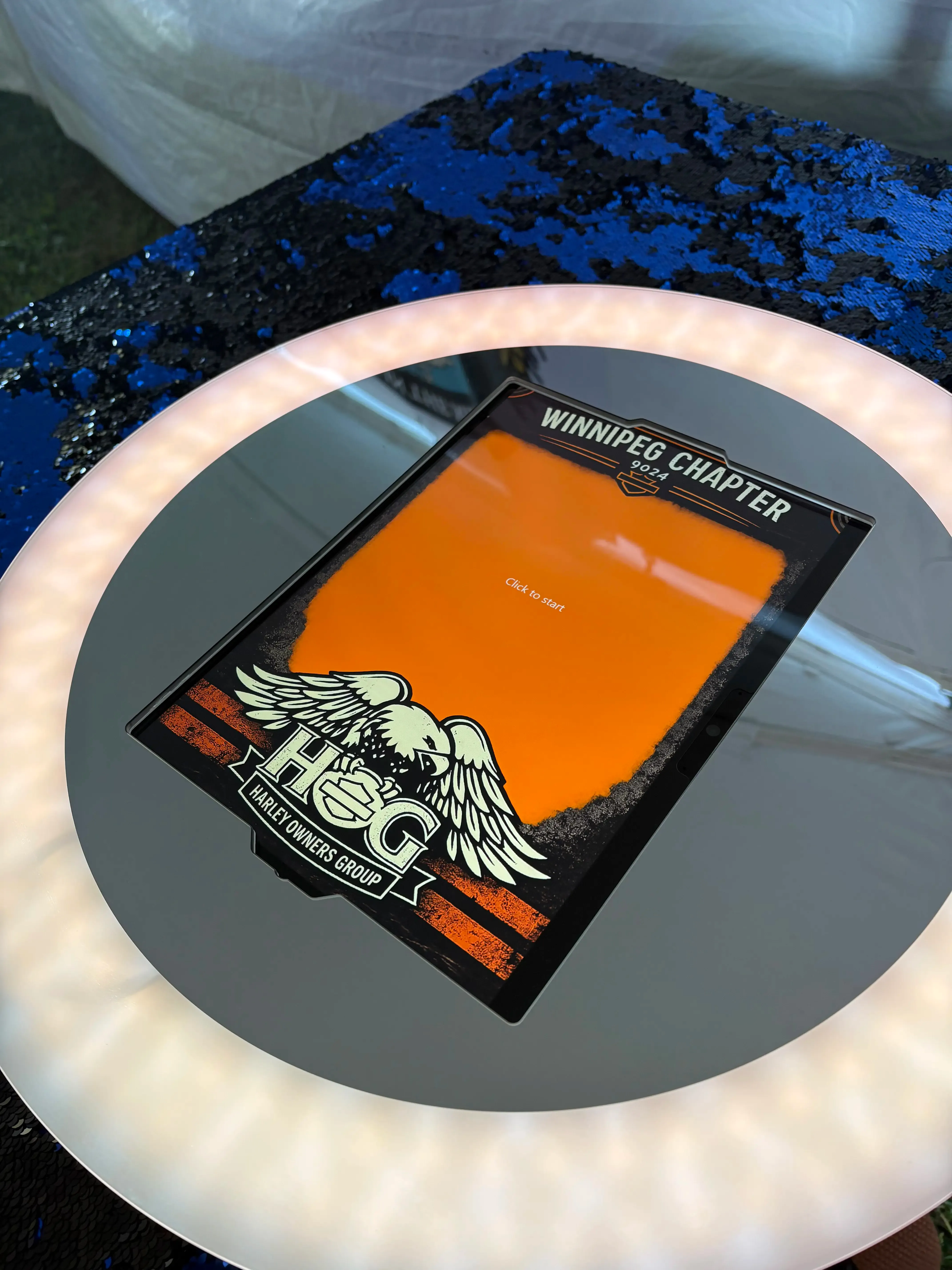 A custom-designed photo booth touch screen displaying a client-branded 'Click to Start' experience