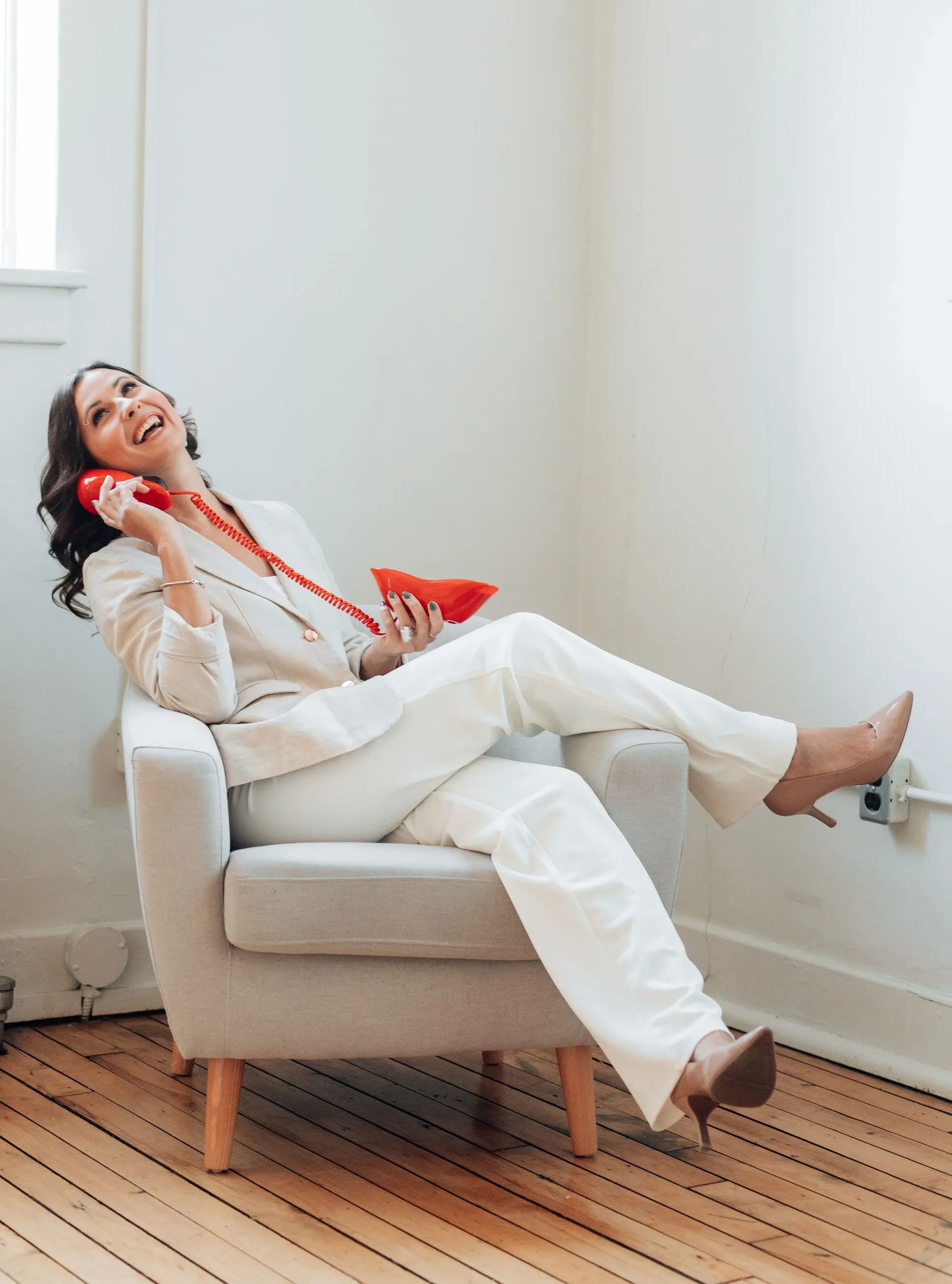 A founder laughing with a vintage red telephone in a modern studio, capturing the playful spirit the team brings to every event