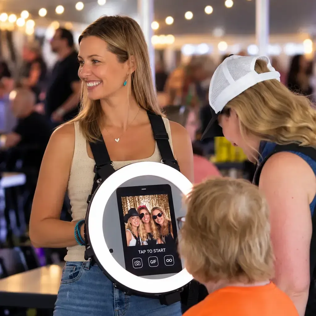 A roaming attendant wearing a handheld ring-light photo rig, ready to capture guests mid-celebration