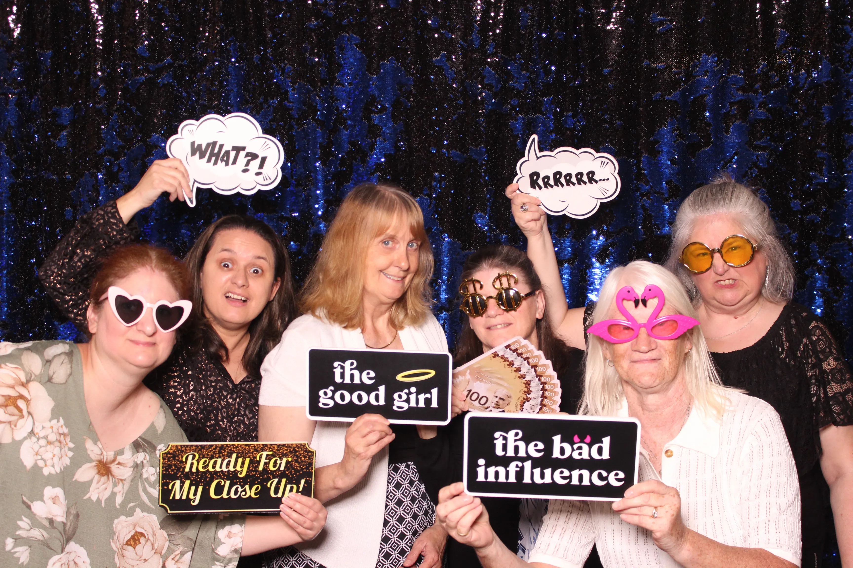 Friends having a blast with props at a photo booth against a sparkling sequin backdrop