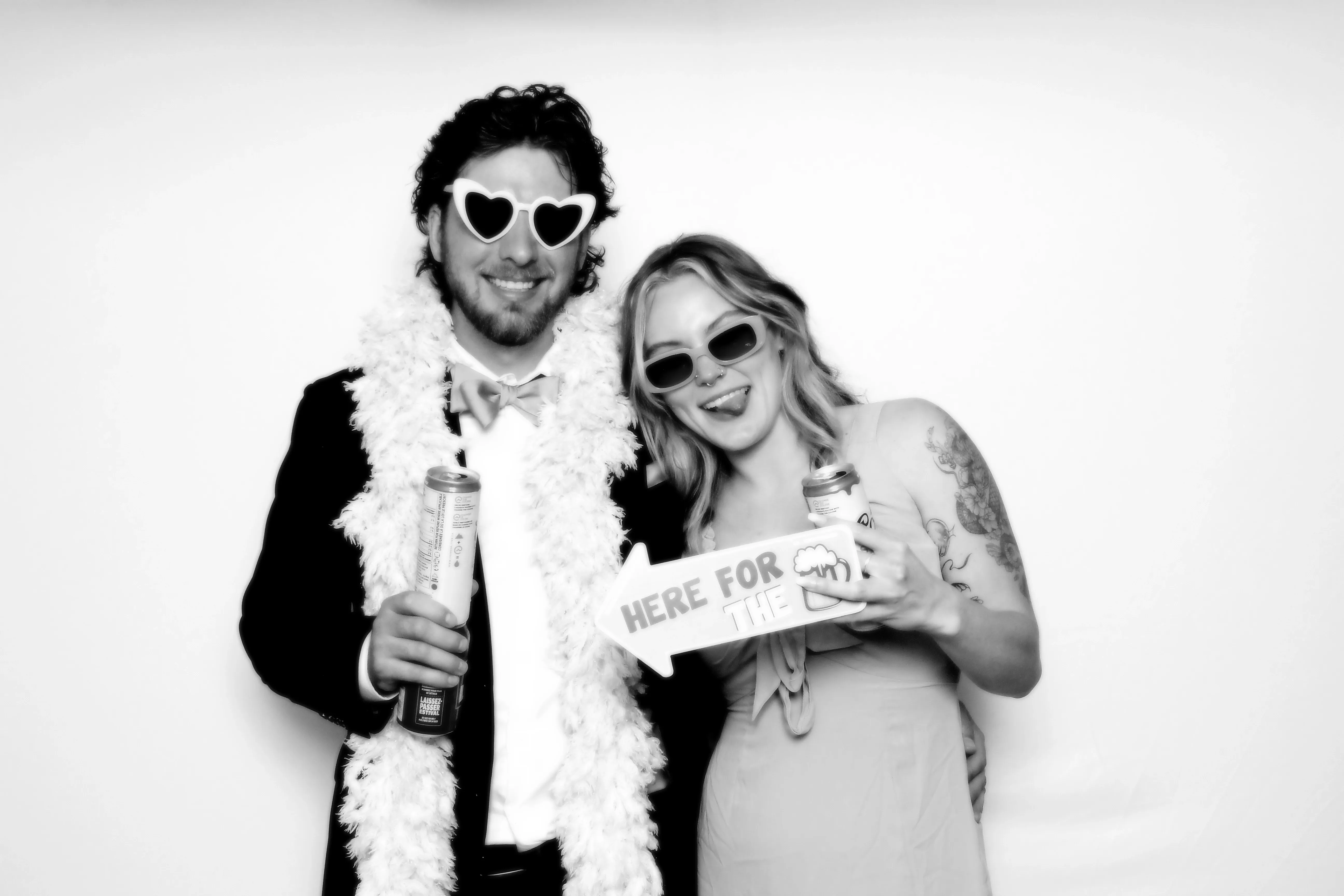 A laughing couple holding fun signs and sparkling drinks at a celebration