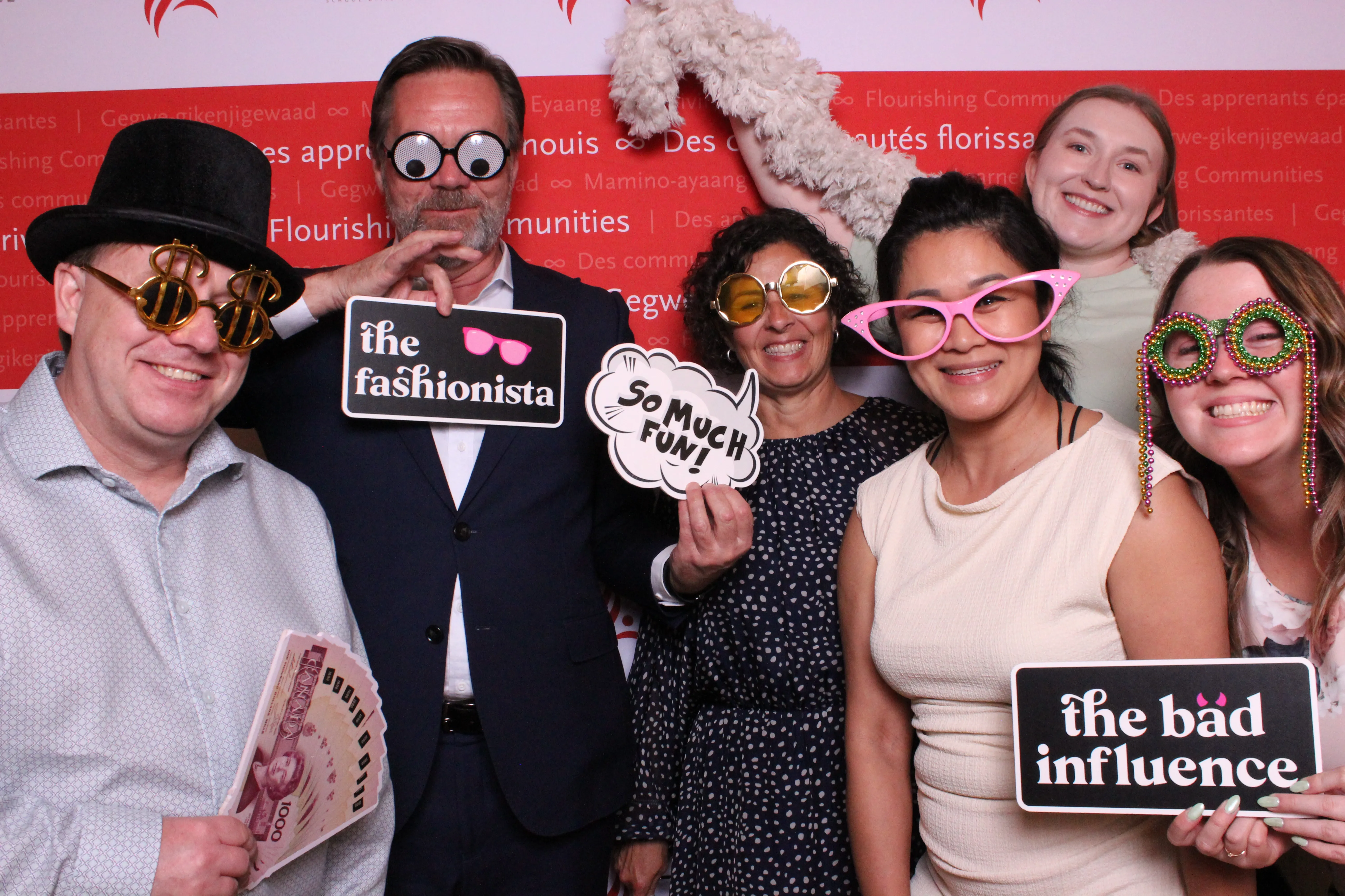 Guests laughing with props against a 'Flourishing Communities'