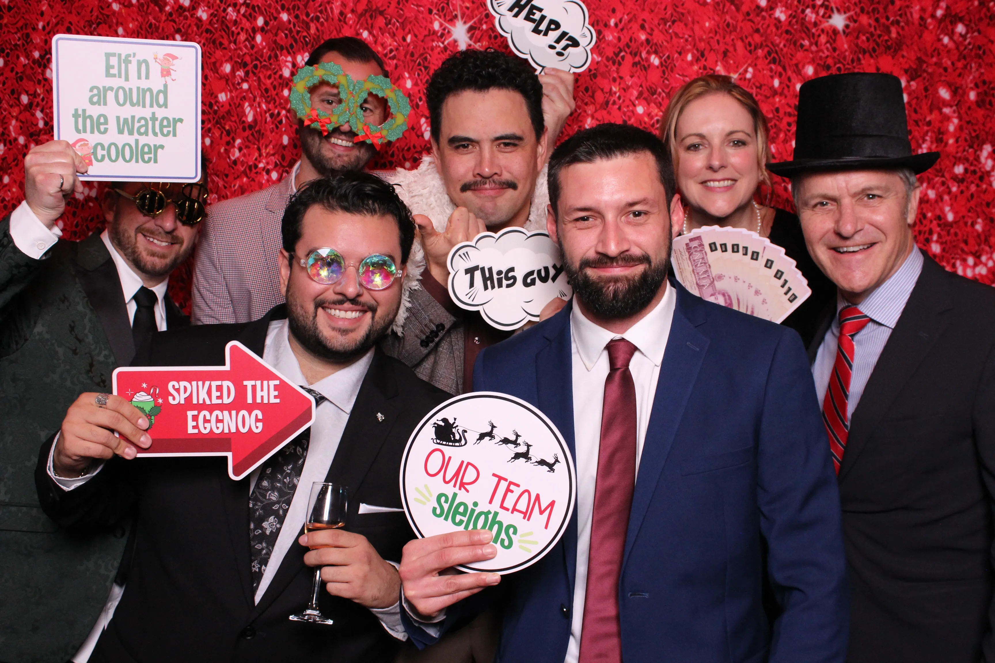 A team celebrating with holiday props against a red sequin backdrop